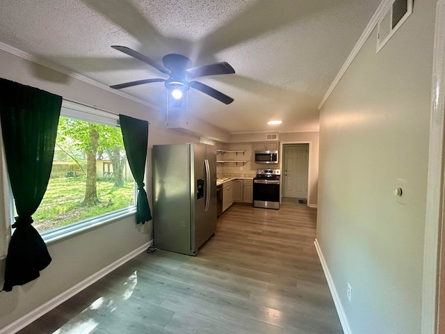 kitchen featuring light hardwood / wood-style floors, ceiling fan, ornamental molding, appliances with stainless steel finishes, and a textured ceiling