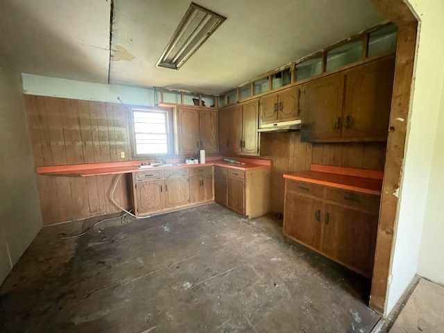 kitchen featuring sink, wood walls, and concrete flooring