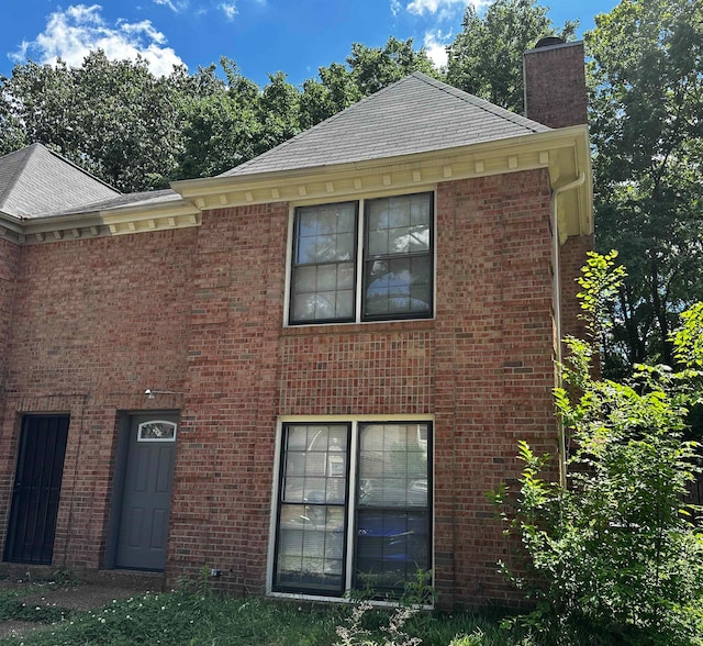 exterior space with brick siding and a chimney