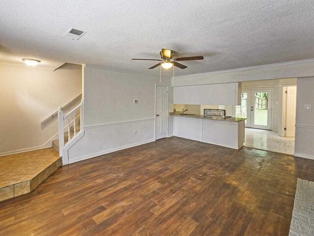 unfurnished living room featuring stairs, wood finished floors, a ceiling fan, and ornamental molding