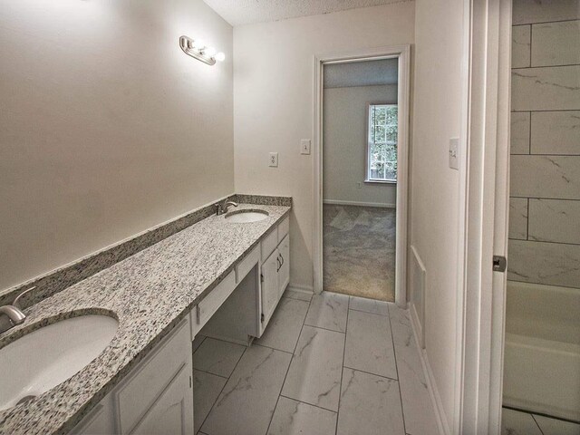 full bathroom with double vanity, a tub to relax in, marble finish floor, and a sink