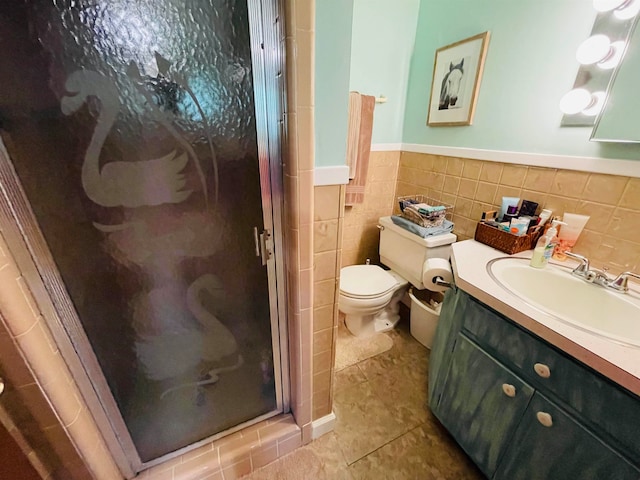 bathroom featuring tile patterned flooring, a shower with door, toilet, tile walls, and vanity