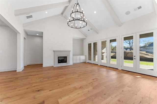 unfurnished living room featuring high vaulted ceiling, light wood-type flooring, beam ceiling, a chandelier, and french doors