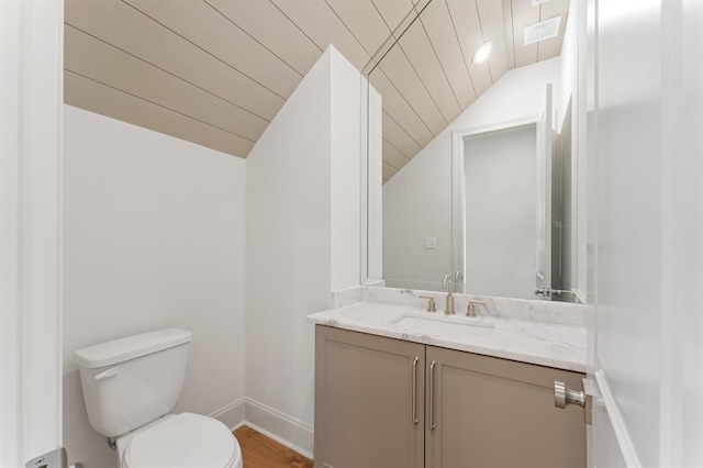 bathroom with vanity, hardwood / wood-style floors, vaulted ceiling, and toilet