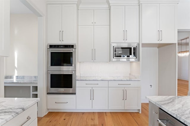 kitchen with light hardwood / wood-style floors, stainless steel appliances, white cabinets, and light stone counters