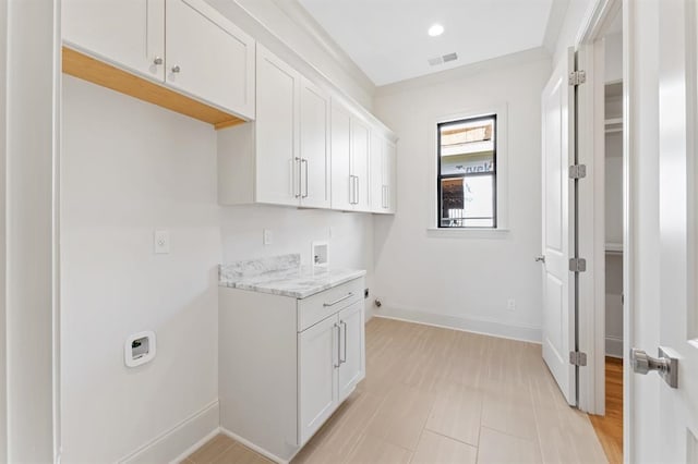 laundry room featuring cabinets, light hardwood / wood-style floors, and hookup for a washing machine