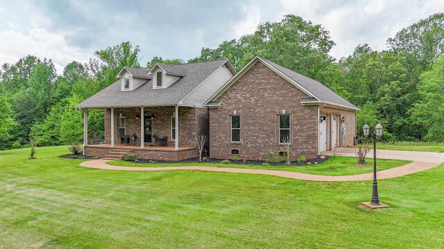 view of front of home featuring covered porch, a garage, and a front lawn