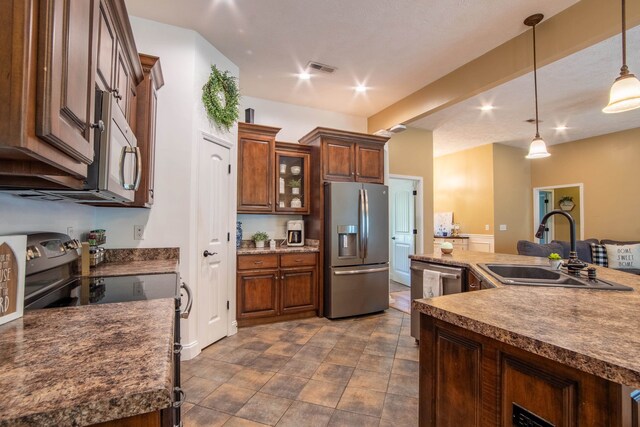 kitchen featuring sink, appliances with stainless steel finishes, pendant lighting, and dark tile flooring