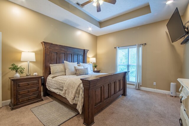 carpeted bedroom featuring ceiling fan and a tray ceiling