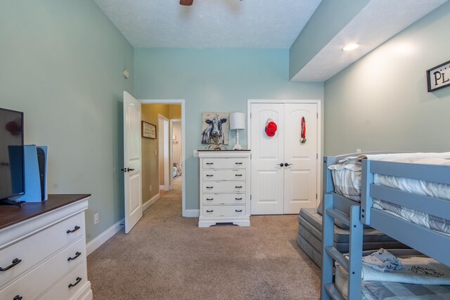 bedroom with a closet, ceiling fan, carpet floors, and a textured ceiling