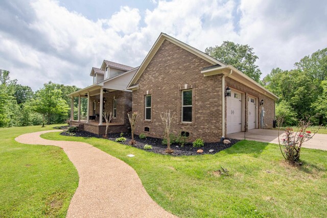 view of side of property featuring covered porch, a yard, and a garage