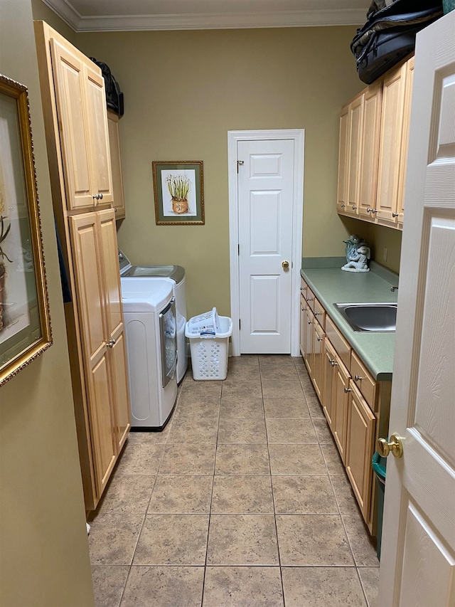 washroom featuring cabinets, crown molding, washing machine and clothes dryer, sink, and light tile flooring