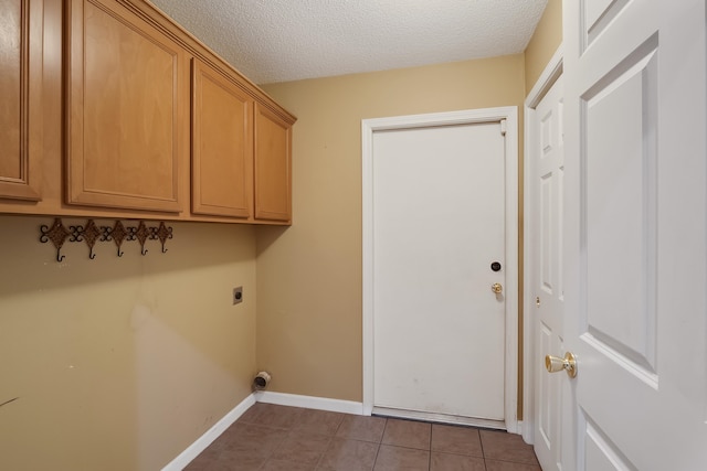 washroom featuring electric dryer hookup, cabinets, a textured ceiling, and tile flooring