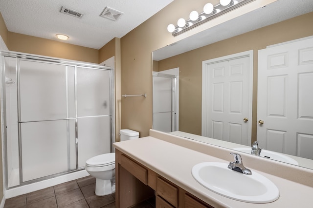 bathroom with large vanity, a shower with shower door, toilet, tile flooring, and a textured ceiling