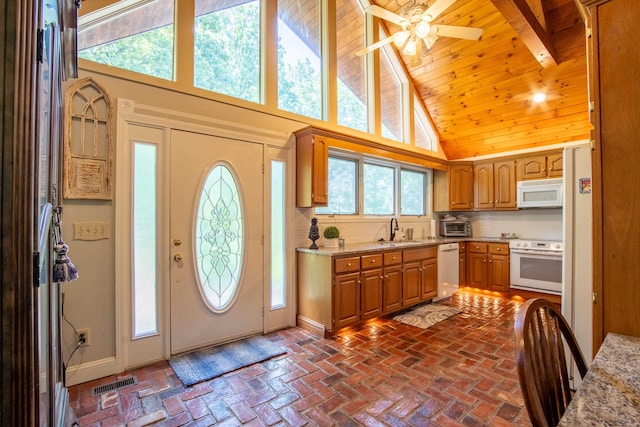 kitchen with high vaulted ceiling, white appliances, sink, tasteful backsplash, and ceiling fan