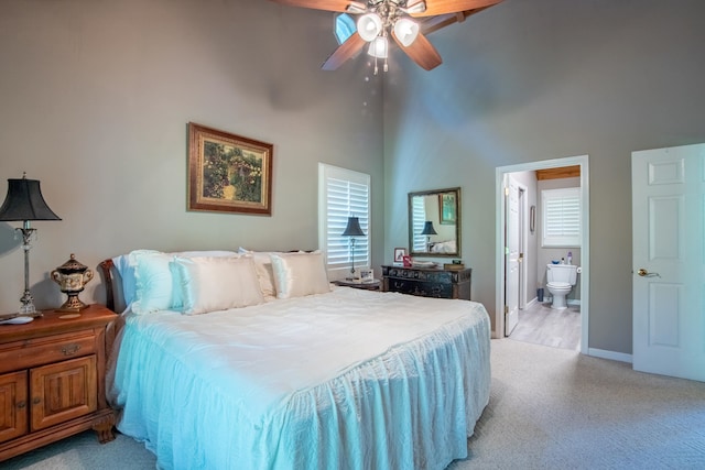 bedroom with ceiling fan, a towering ceiling, ensuite bathroom, and multiple windows