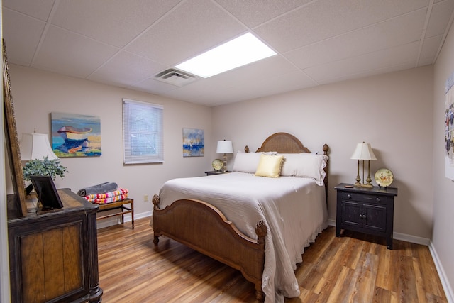 bedroom with light wood-type flooring and a paneled ceiling