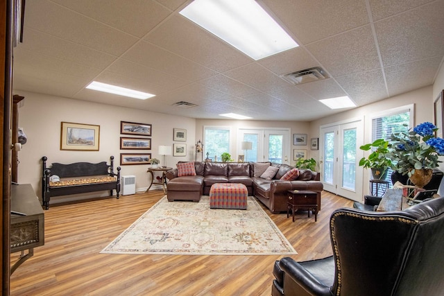 living room featuring wood-type flooring, french doors, and a paneled ceiling