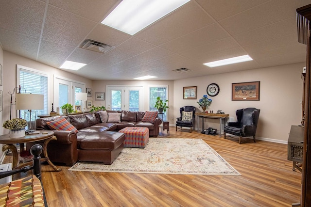 living room featuring a drop ceiling, french doors, and hardwood / wood-style flooring