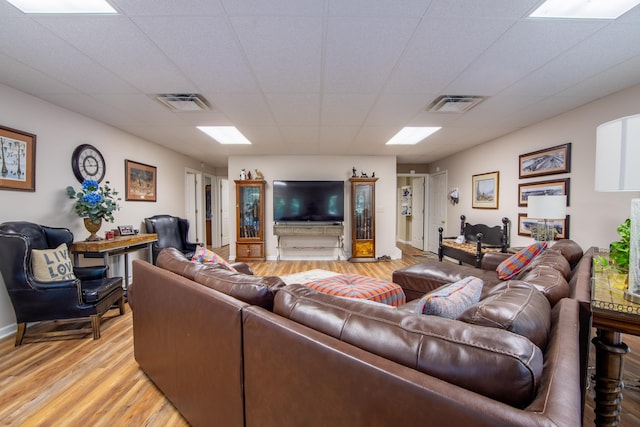 living room featuring light wood-type flooring and a paneled ceiling