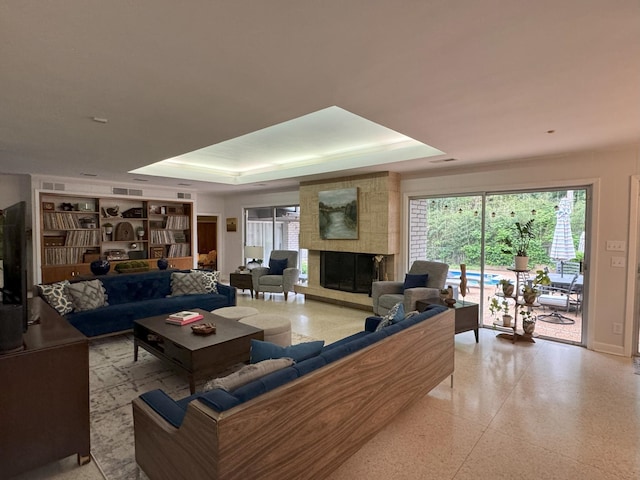 living room with a large fireplace and a raised ceiling