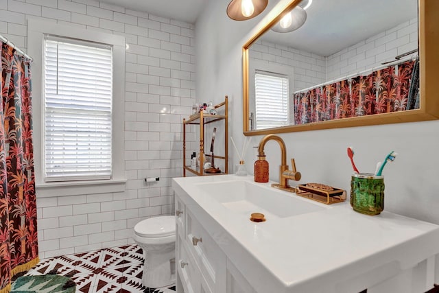 bathroom with tile walls, walk in shower, tile patterned floors, vanity, and toilet