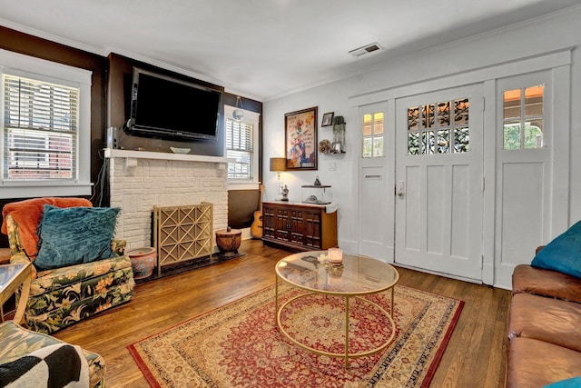 living room featuring a fireplace, ornamental molding, and hardwood / wood-style floors