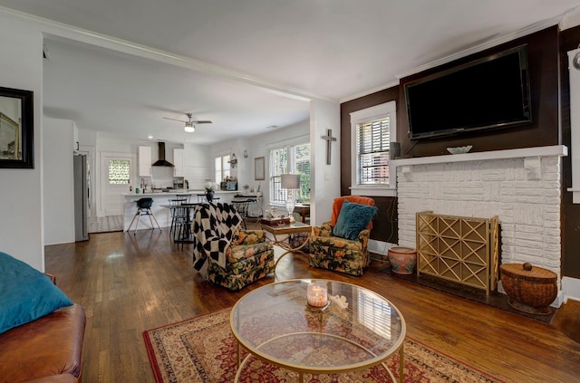 living room with wood-type flooring, a fireplace, ornamental molding, and ceiling fan