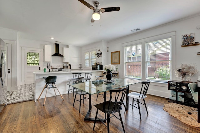 dining room with ceiling fan, crown molding, and dark wood-type flooring