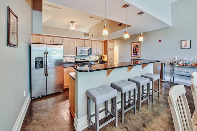 kitchen with backsplash, stainless steel appliances, light brown cabinetry, and hanging light fixtures