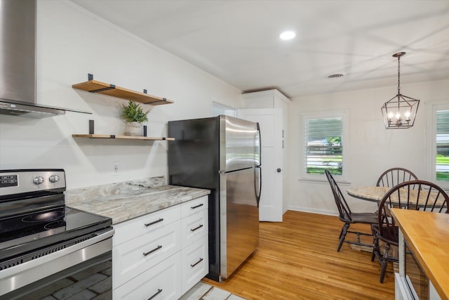 kitchen with wall chimney range hood, light hardwood / wood-style floors, stainless steel appliances, white cabinets, and pendant lighting