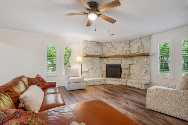 living room featuring a stone fireplace, ornamental molding, ceiling fan, and hardwood / wood-style floors