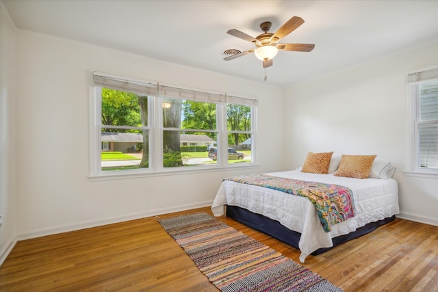 bedroom with wood-type flooring, multiple windows, and ceiling fan