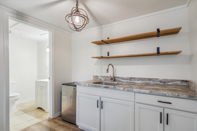 kitchen with light stone counters, hanging light fixtures, crown molding, white cabinetry, and sink