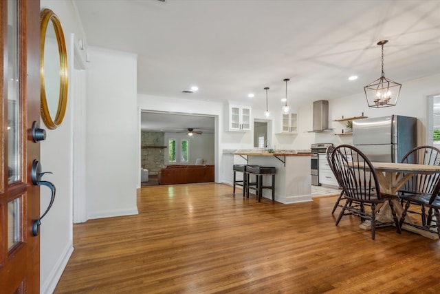 interior space with ceiling fan with notable chandelier, appliances with stainless steel finishes, white cabinets, and wood-type flooring