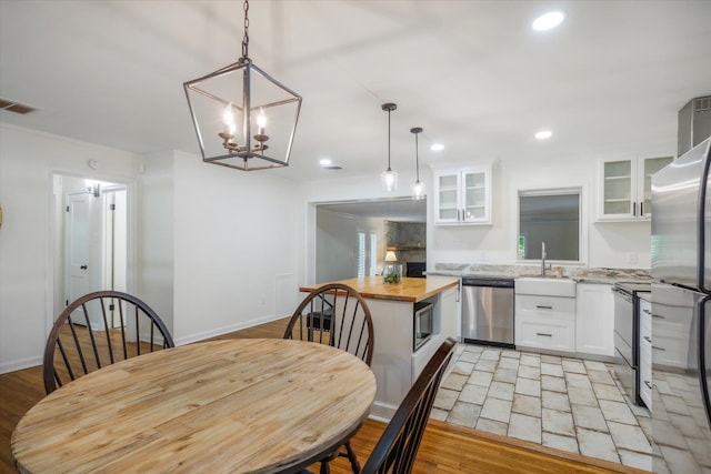 dining area featuring sink, an inviting chandelier, and light tile floors