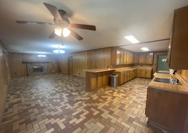 kitchen with wooden walls, ceiling fan, a fireplace, and sink