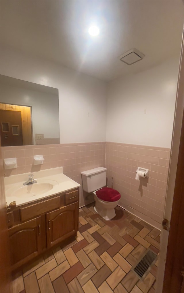 bathroom with tile flooring, tile walls, backsplash, vanity, and toilet