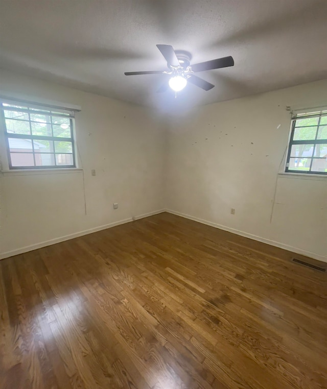 empty room featuring ceiling fan, a healthy amount of sunlight, and wood-type flooring