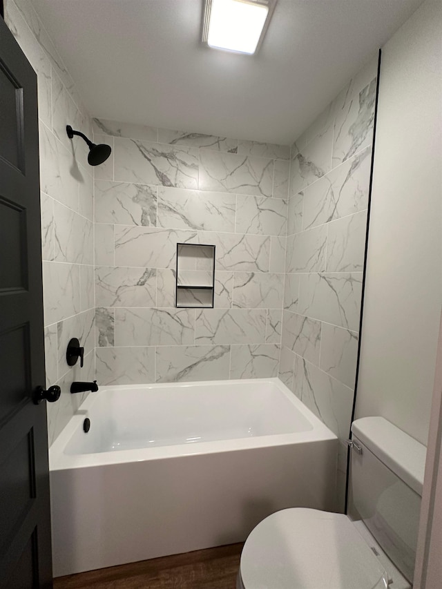 bathroom with tiled shower / bath combo and toilet