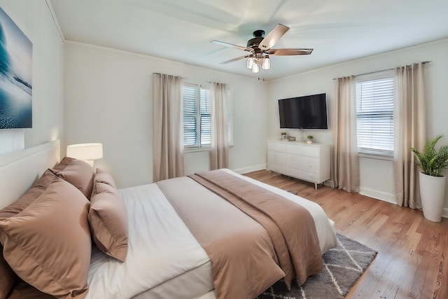 bedroom featuring ornamental molding, ceiling fan, light wood-type flooring, and multiple windows