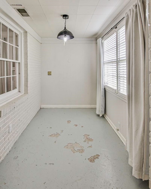 empty room featuring crown molding and brick wall