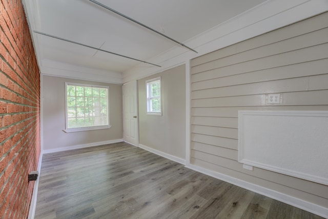 empty room with hardwood / wood-style flooring and brick wall