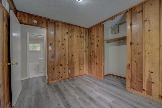 empty room featuring wood walls, light hardwood / wood-style flooring, and a textured ceiling