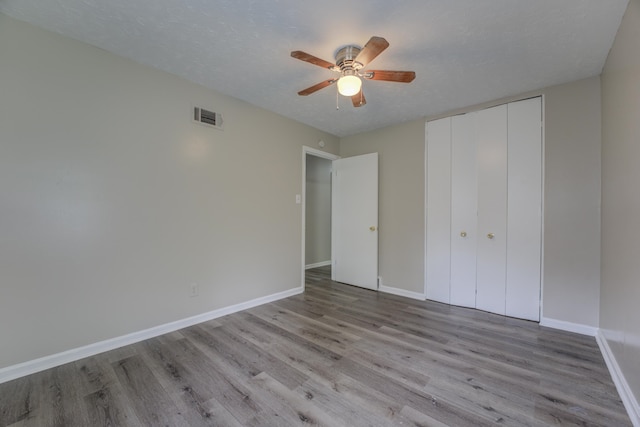 unfurnished bedroom featuring a textured ceiling, a closet, ceiling fan, and hardwood / wood-style floors