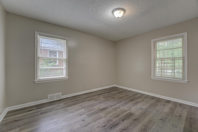 spare room with a textured ceiling and hardwood / wood-style flooring