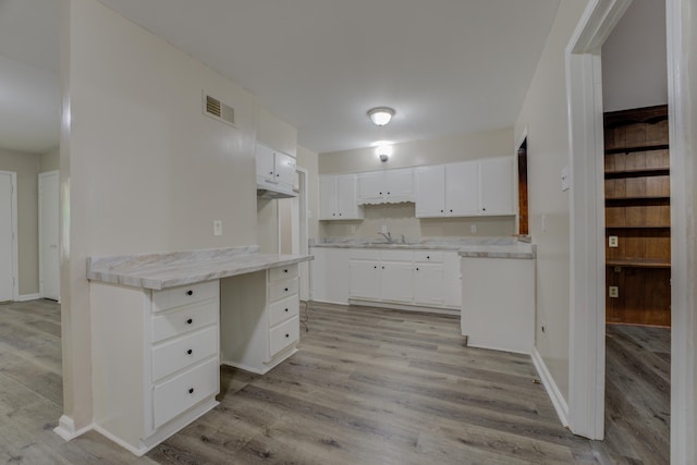 kitchen featuring sink, white cabinetry, and light wood-type flooring