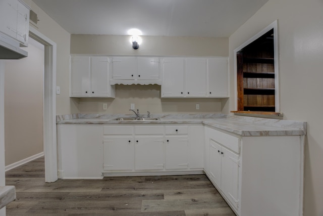 kitchen featuring sink, white cabinets, and light wood-type flooring