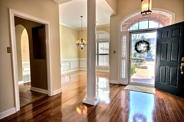 foyer featuring ornamental molding, decorative columns, a chandelier, and dark hardwood / wood-style flooring