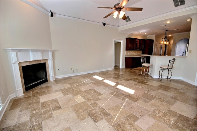 unfurnished living room with ceiling fan with notable chandelier, ornamental molding, and a tiled fireplace